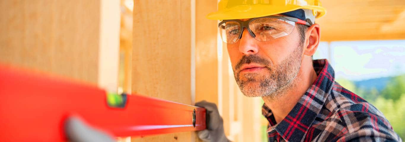 specjalista od domów szkieletowych konstroluje poziom ściany domu skandynawskiego