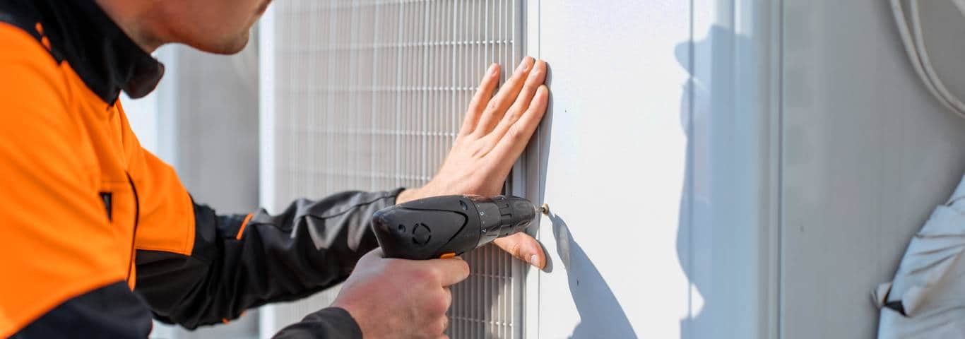 specjalista w kasku montuje pompę ciepła