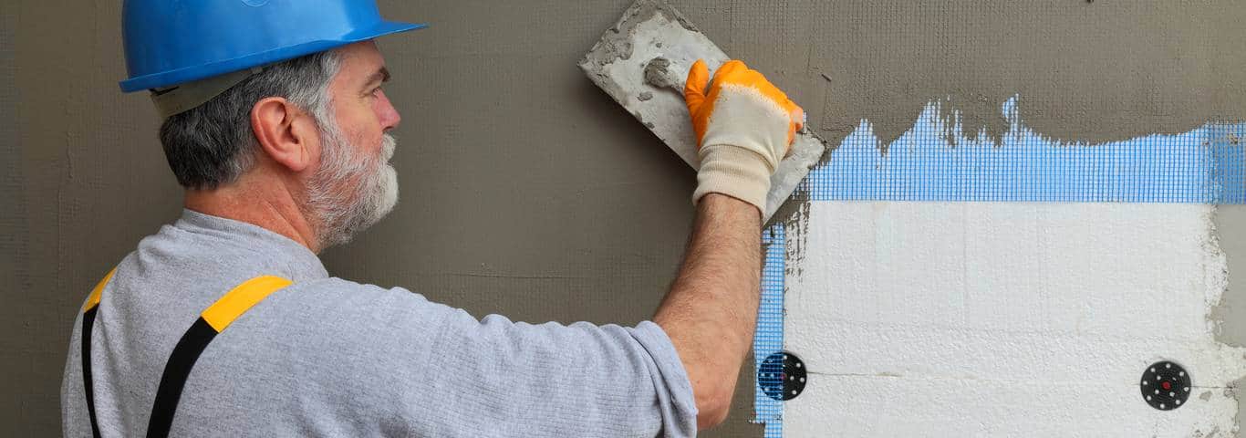 fachowiec w trakcie zbrojenia elewacji rozprowadza zaprawę na siatce elewacyjnej