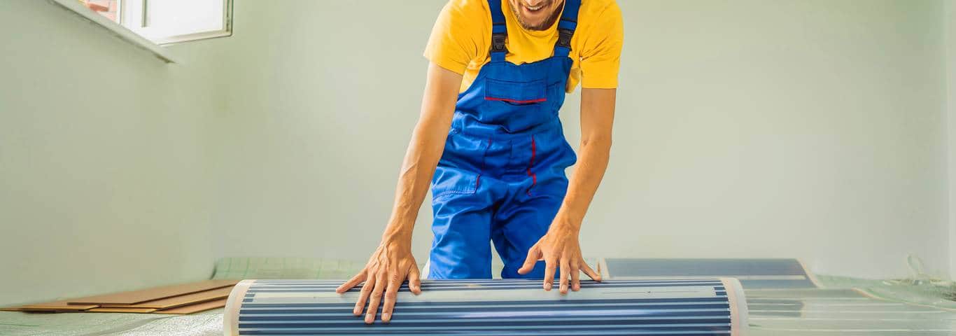 instalator rozwija folię pod ogrzewanie podłogowe