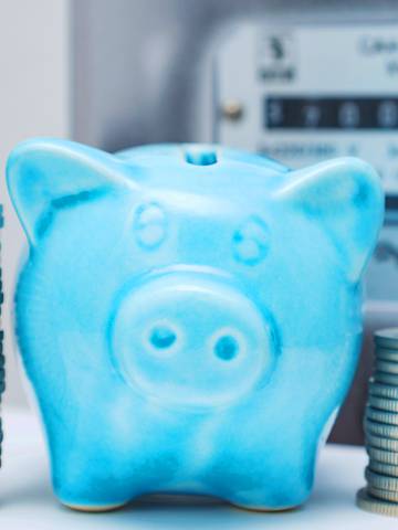 niebieska świnka skarbonka obok licznika energii elektrycznej i monet