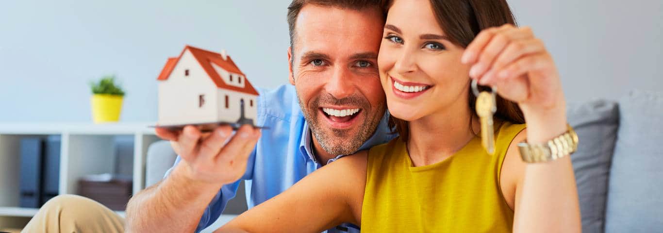 szczęśliwa para trzyma klucze i model domu