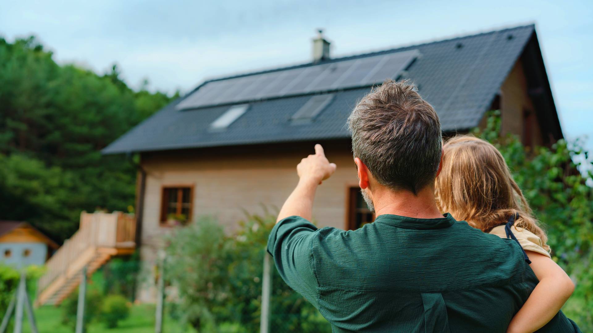tata pokazujący córce dom z instalacją fotowoltaiczną o mocy 6 kW na dachu