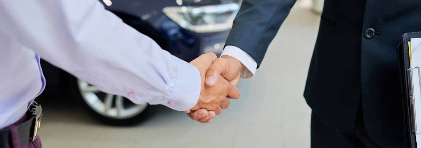 uścisk dłoni leasingodawcy i leasingobiorcy na tle samochodu