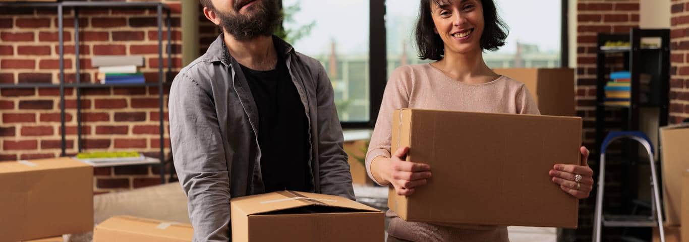 uśmiechnięta para trzyma pudła przeprowadzkowe
