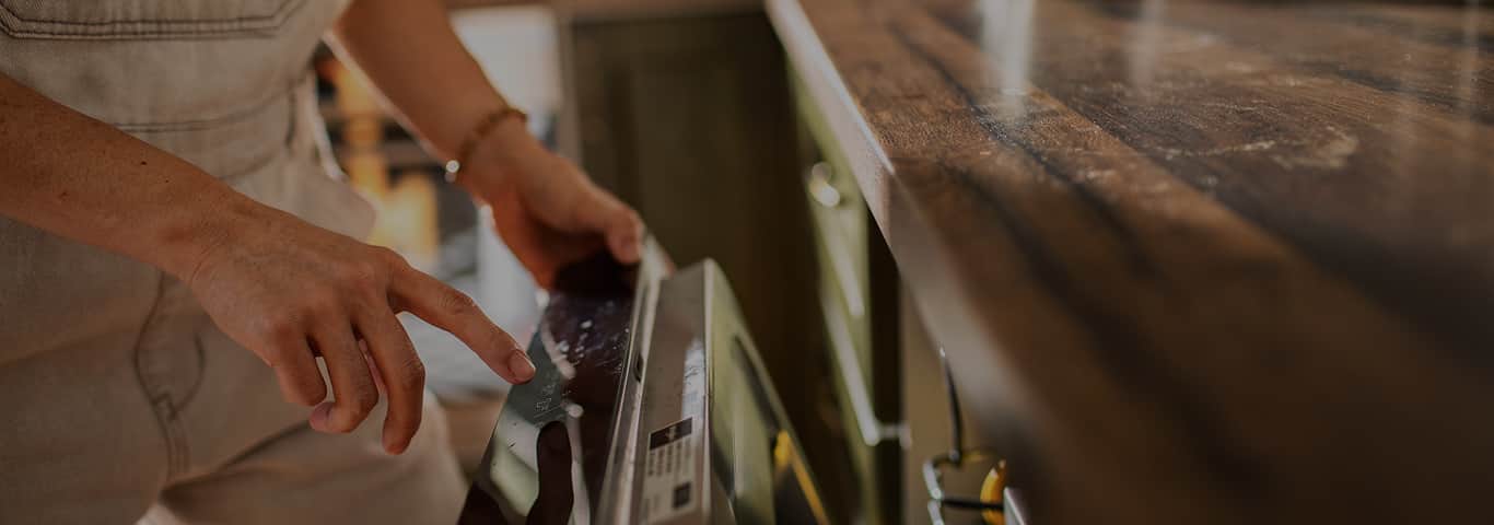 Osoba uruchamiająca zmywarkę w zabudowie kuchennej