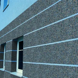 Elewacja budynku pokryta mozaikowym tynkiem akrylowym w odcieniach szarości i brązu, z poziomymi pasami jasnego błękitu.