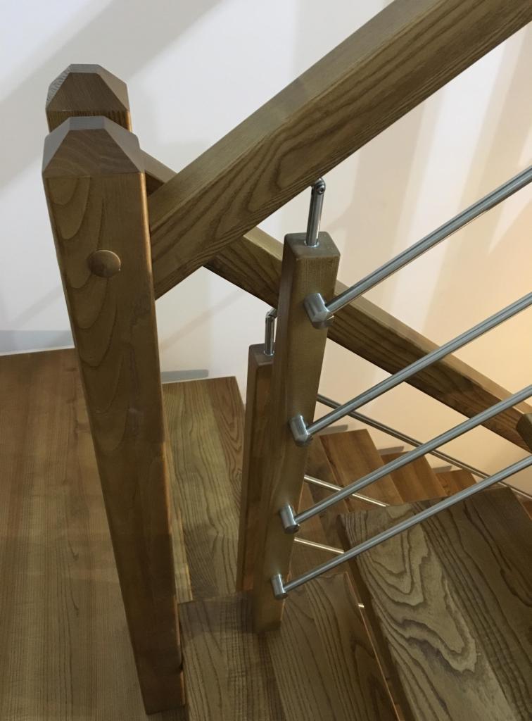 Fragment drewnianych schodów z metalowymi relingami, widok z góry, ukazujący naturalny rysunek drewna i solidną konstrukcję.