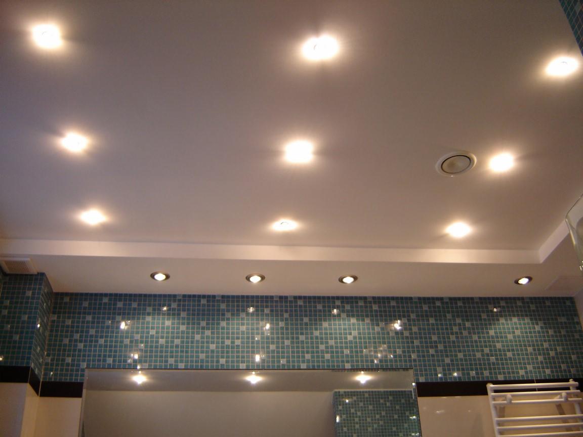 Jasna łazienka z mozaiką w odcieniach turkusu i licznymi punktowymi źródłami światła w suficie podwieszanym.