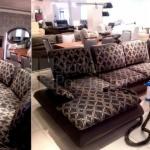 Ustawiona sofa w salonie meblowym z widocznymi innymi meblami w tle. Sofa z wzorem w romby, oświetlona światłem dziennym. Widok na ekspozycję mebli.