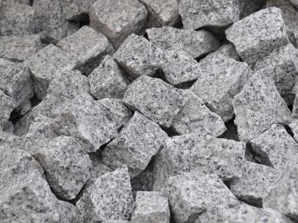 Kupa szarej kostki granitowej o frakcji 4/6 - 8/11 - 15/17 oferowanej przez firmę z Izdebnika, ułożona w nieładzie, z bliska.