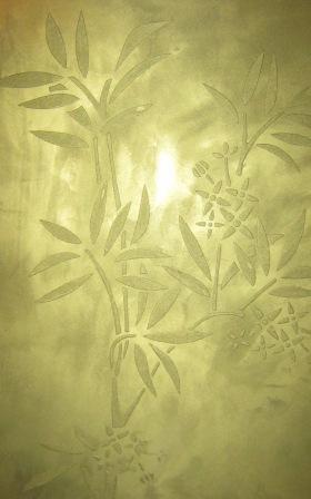 Dekoracyjna ściana w odcieniach złota z delikatnym wzorem bambusa i kwiatów, wykonana techniką tynku strukturalnego.