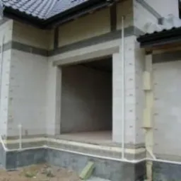 Surowy stan budynku z widocznymi instalacjami rur na zewnątrz ściany, przygotowany pod montaż systemu centralnego odkurzania.