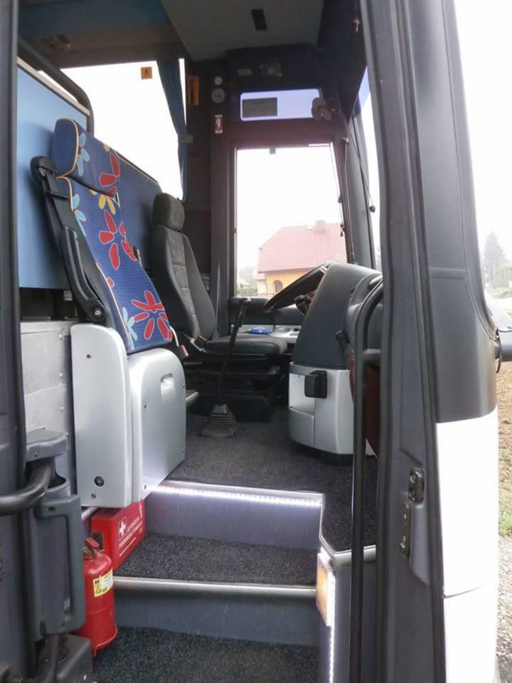 Wnętrze autobusu turystycznego z widocznym stanowiskiem kierowcy, schodkami z oświetleniem LED i apteczką pierwszej pomocy.