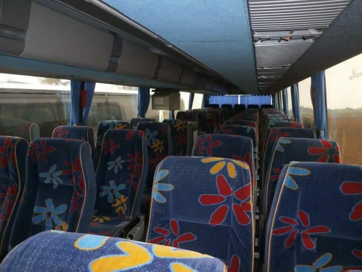 Wnętrze autobusu turystycznego z niebieskimi fotelami w kwiaty, widok z przodu na puste siedzenia i okna.