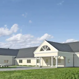 Wizualizacja projektu parterowego domu z jasną elewacją, grafitowym dachem i kolumnami wejściowymi, otoczonego zielonym trawnikiem i drzewami, z widocznym fragmentem nieba z chmurami.