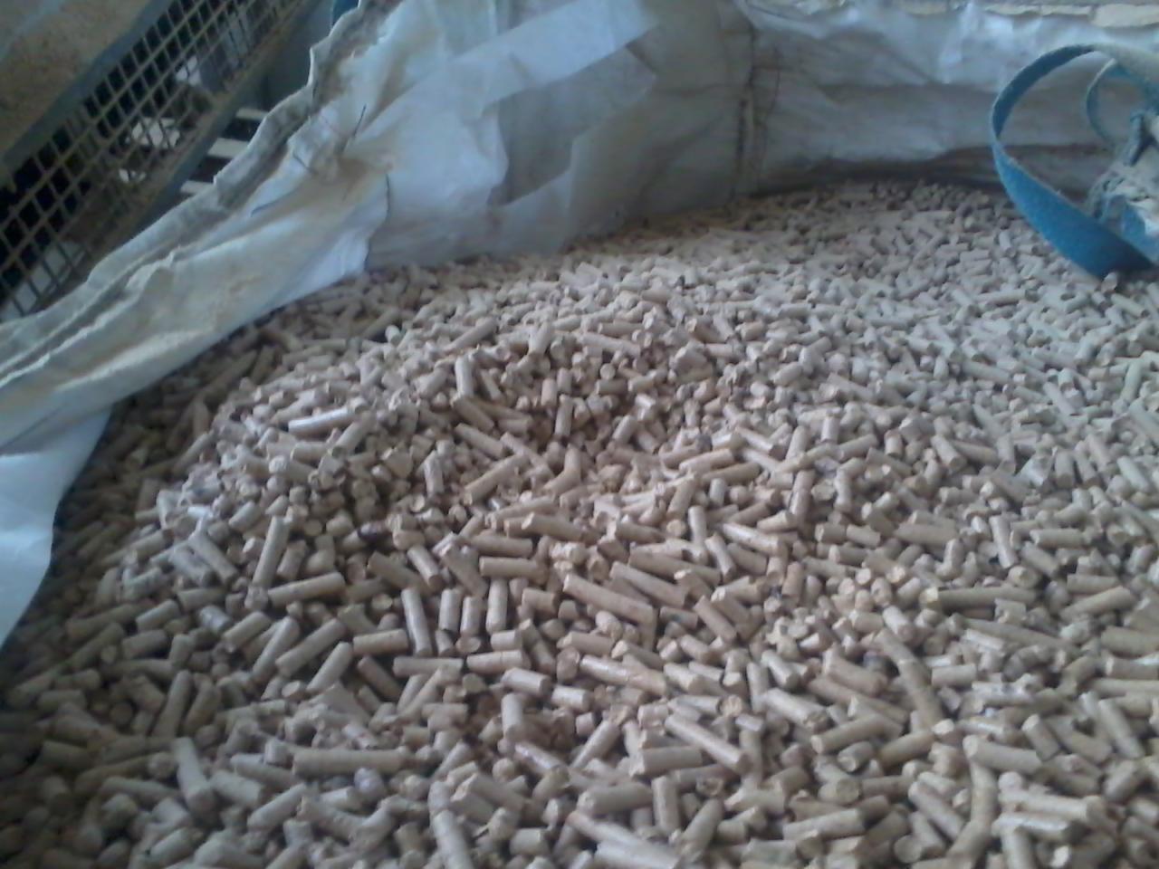 Jasne pellety drzewne 6mm w worku, widoczne drobne nierówności i pył drzewny.
