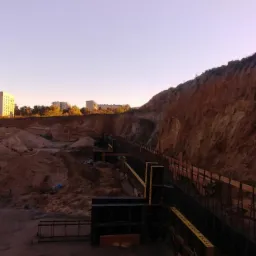 Skarpa zabezpieczona szalunkiem w Redzie, widoczne pryzmy ziemi i budynki w tle, wczesny poranek.