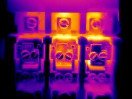Termowizyjny obraz rozdzielnicy elektrycznej z wyraźnie zaznaczonymi punktami o podwyższonej temperaturze, wskazującymi potencjalne problemy.