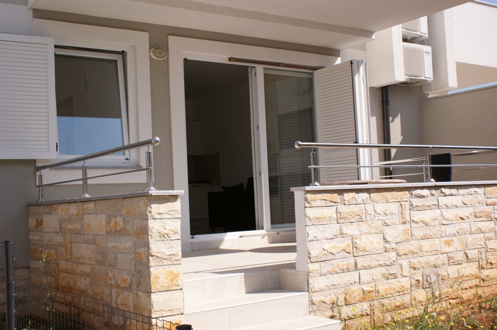 Wejście do apartamentu w Chorwacji z kamienną balustradą, białymi okiennicami i klimatyzacją na zewnątrz.