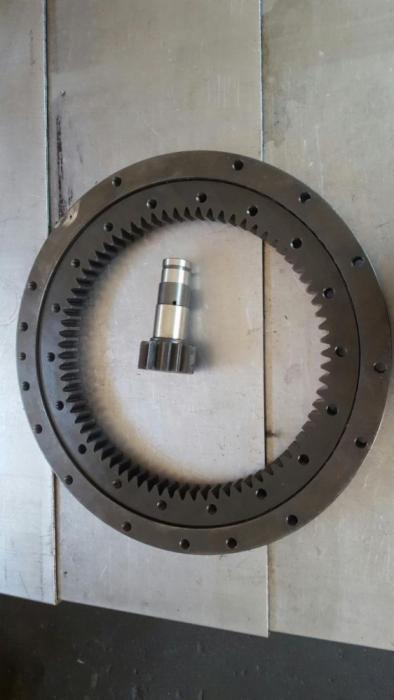 Obrabiane koło zębate z wewnętrznym uzębieniem i mała zębatka na metalowym blacie. Widoczne ślady obróbki.