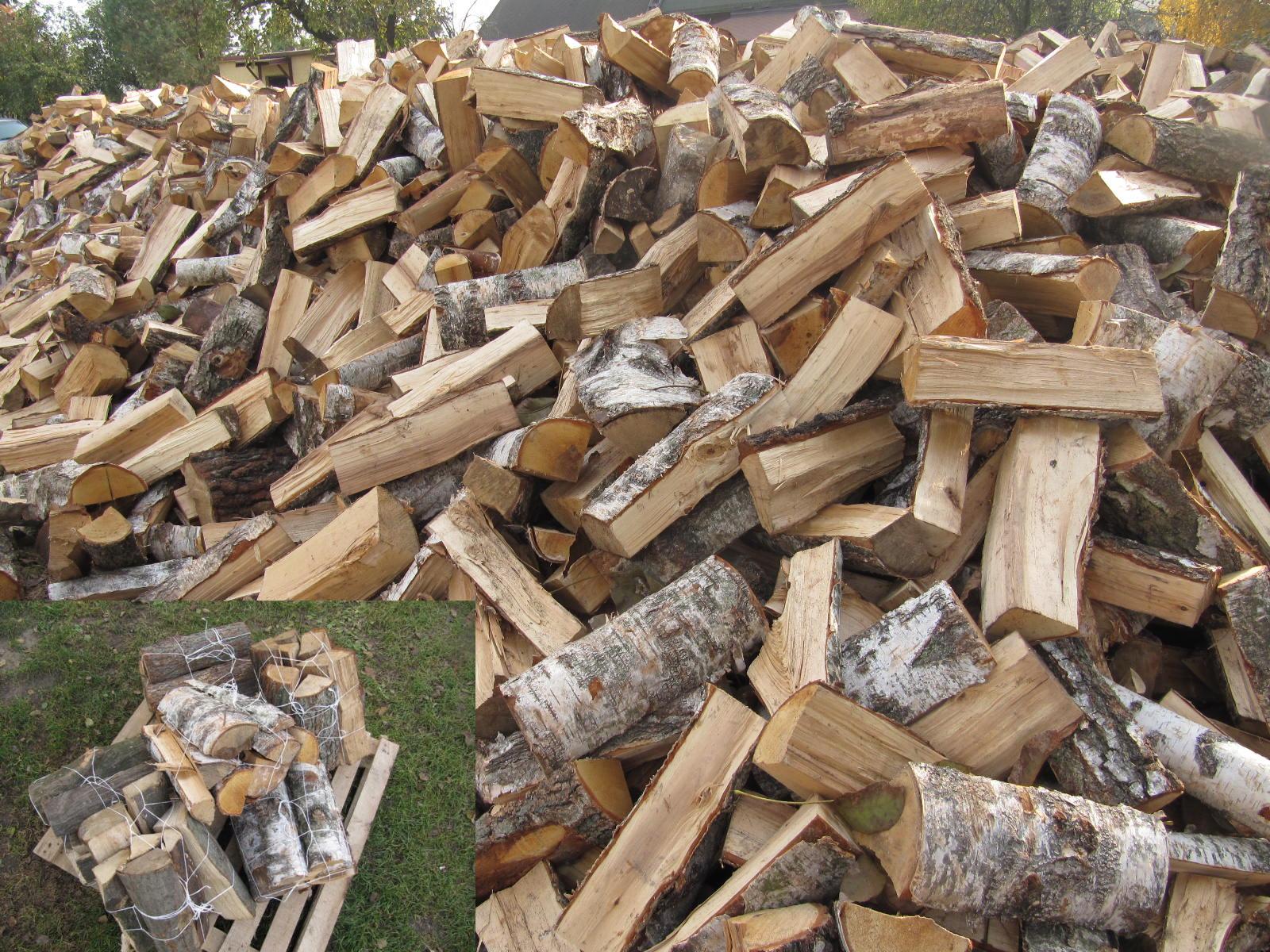Stos pociętego drewna brzozowego na opał, część ułożona luzem, a część spakowana w siatki na palecie.