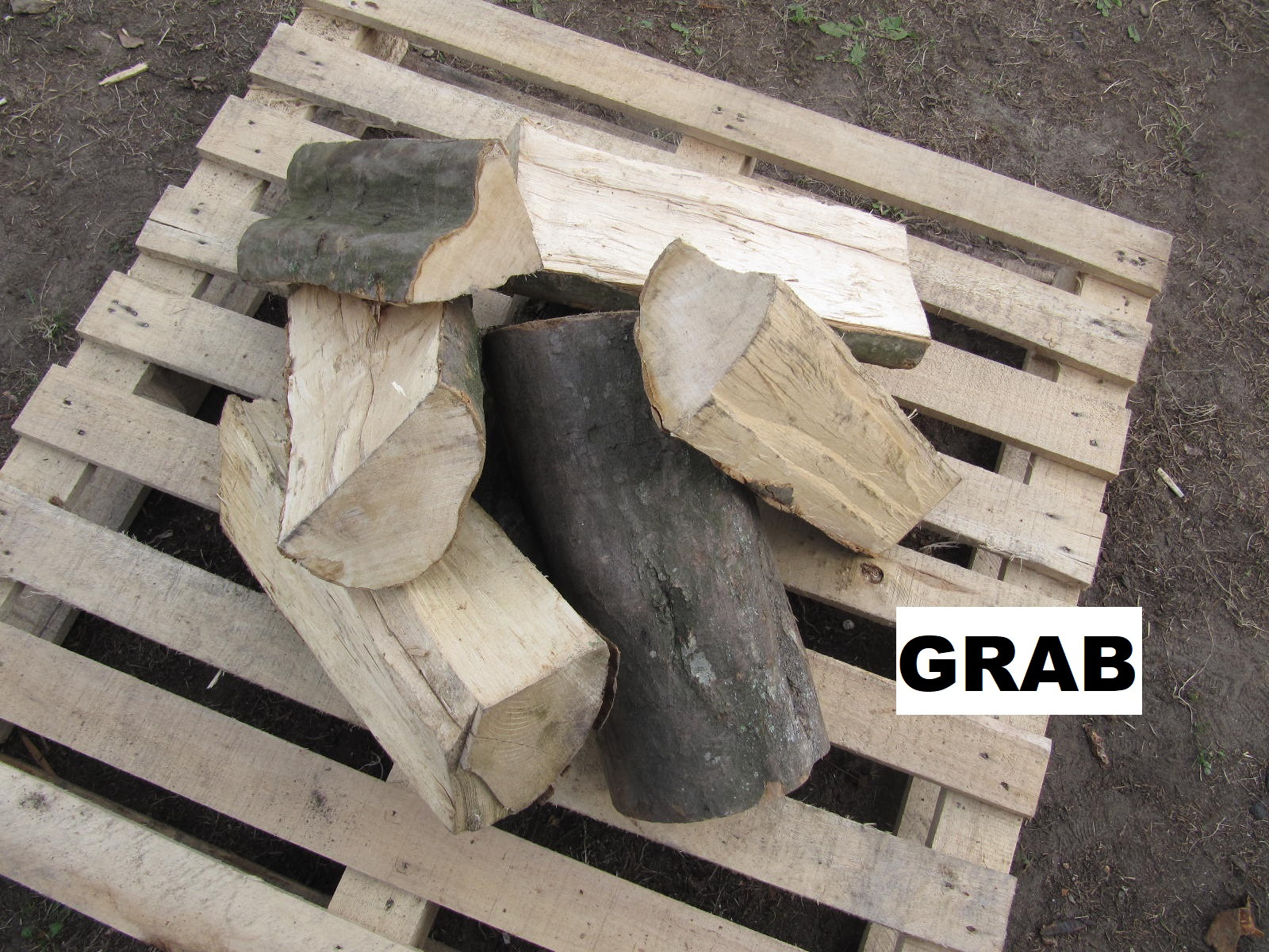 Kłody drewna ułożone na drewnianej palecie, widoczne słoje i kora.
