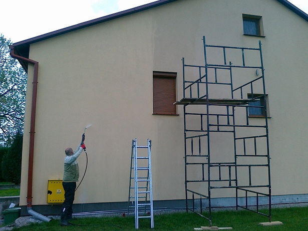 Czyszczenie elewacji domu w Jarosławiu za pomocą myjki ciśnieniowej, widoczne rusztowanie i drabina.