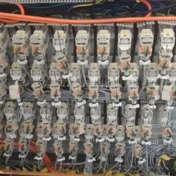 Elektromeister Kaminski - Rozbudowana szafa sterownicza z licznymi modułami elektrycznymi, okablowaniem w peszlach i listwach, widok z bliska na połączenia i złączki.