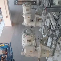 Elektromeister Kaminski - Widok z góry na zainstalowany system rur i silników elektrycznych w hali przemysłowej, z widocznym podnośnikiem koszowym w lewym dolnym rogu.