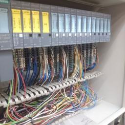 Elektromeister Kaminski - Rozdzielnica elektryczna z modułami sterującymi Siemens Simatic ET 200SP i licznymi przewodami uporządkowanymi w korytkach, widoczne oznaczenia modułów KF10, KF11, KF20, KF21, KF30.