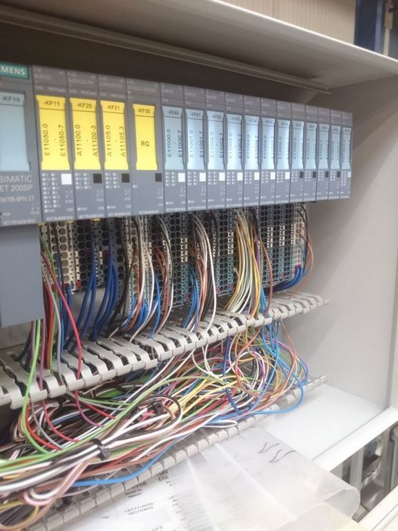 Rozdzielnica elektryczna z modułami sterującymi Siemens Simatic ET 200SP i licznymi przewodami uporządkowanymi w korytkach, widoczne oznaczenia modułów KF10, KF11, KF20, KF21, KF30.