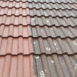 Częściowo oczyszczony dach z czerwonej dachówki, wyraźna różnica między umytą a brudną powierzchnią, widoczne ślady mchu i zabrudzeń.