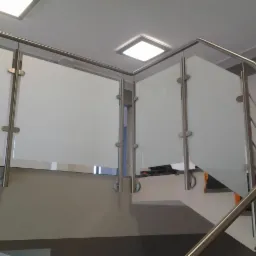 Szklana balustrada ze stali nierdzewnej na schodach spiralnych. Nowoczesny design, jasne wnętrze, widok z dołu na górę.