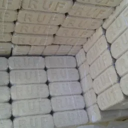 Ułożone w stosy kostki brykietu drzewnego RUF, owinięte folią, widoczne z bliska pod kątem.