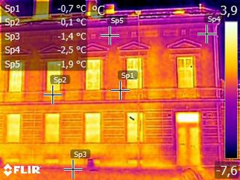 Termowizyjne zdjęcie elewacji budynku, wskazujące na straty ciepła w okolicach okien i dachu, oznaczone punktami pomiarowymi Sp1 do Sp5 z odpowiadającymi temperaturami.