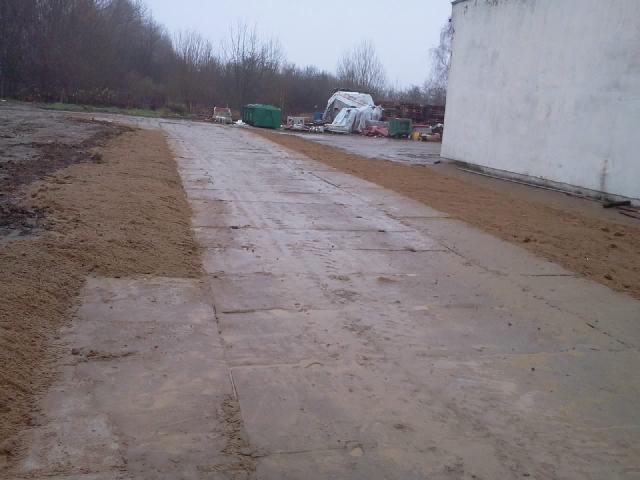 Ułożone płyty betonowe i obsypana ziemią krawędź terenu w Szczecinie. Przygotowanie podłoża pod budowę lub utwardzenie terenu. Widoczne materiały budowlane w tle.