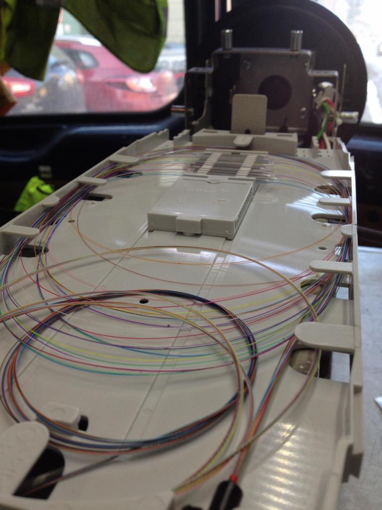 Rozdzielnica światłowodowa z ułożonymi kolorowymi kablami światłowodowymi wewnątrz obudowy, widoczne kable w różnych kolorach oraz elementy montażowe.