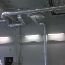 Krystwik wentylacja klimatyzacja - Srebrne rury wentylacyjne pod sufitem w budynku komercyjnym, widoczne drabiny i oświetlenie