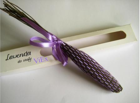 Suszona lawenda w ozdobnym, podłużnym pudełku z okienkiem, przewiązana fioletową wstążką.