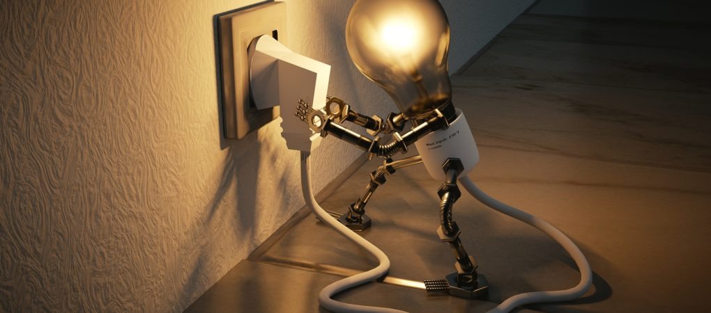 Stylizowana żarówka z metalowymi elementami, imitująca robota, podłącza wtyczkę do gniazdka elektrycznego na teksturowanej ścianie