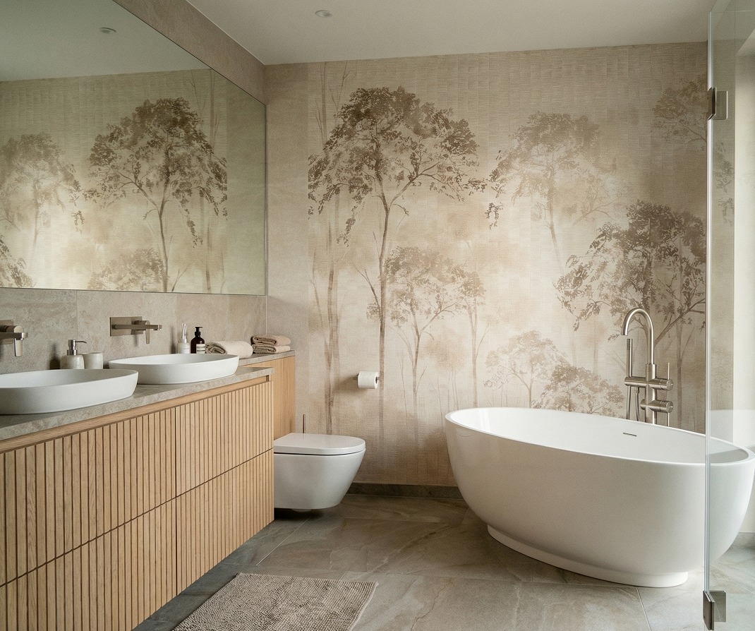 Jasna łazienka z tapetą w motywie drzew, owalną wanną i umywalką nablatową na drewnianej szafce. Minimalistyczny design, neutralna kolorystyka, nowoczesne baterie.