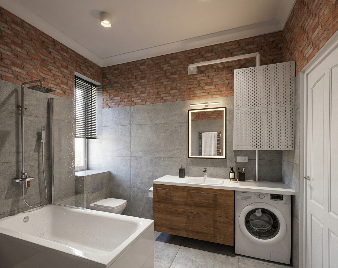 Nowoczesna łazienka z ceglaną ścianą, szarą glazurą i drewnianą szafką pod umywalką. Widoczna wanna, toaleta i pralka. Oświetlenie LED nad lustrem.