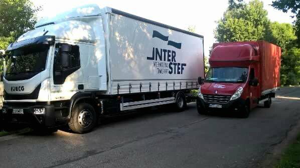 Biała ciężarówka Iveco z naczepą i czerwony bus Renault Master zaparkowane obok siebie na asfaltowej drodze, widoczne logo firmy transportowej 'INTER STEF' na naczepie.