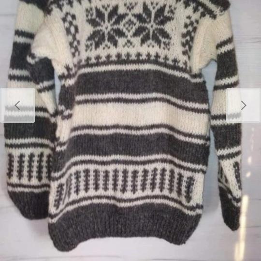 Ręcznie robiony sweter z grubymi, szarymi i kremowymi pasami oraz wzorem śnieżynek na górze, widoczne ściegi.