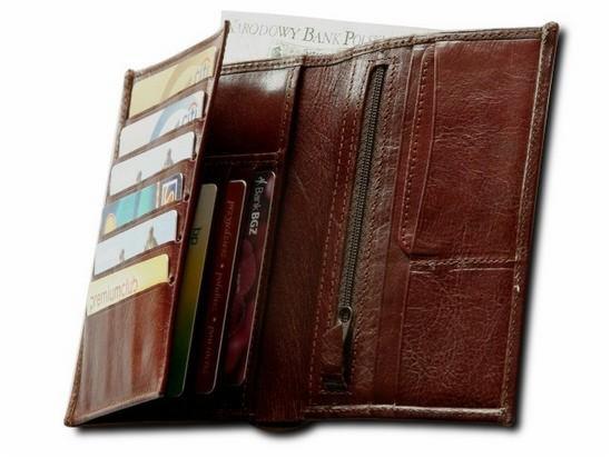 Otwarty, brązowy, skórzany portfel z widocznymi kartami kredytowymi i banknotem Narodowego Banku Polskiego.
