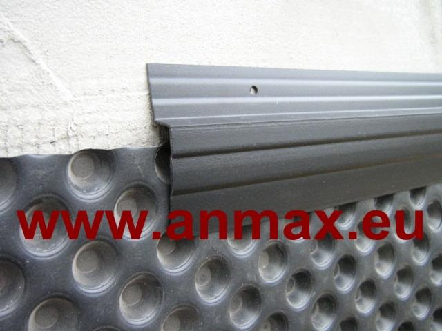 Czarna listwa zakończeniowa ANMAX PROFILE zamontowana na folii kubełkowej przy fundamencie budynku z surowym betonem.