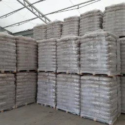 Skladowane na paletach, owinięte folią worki z brykietem, widoczne w magazynie w Łukowie, pod zadaszeniem o stalowej konstrukcji.