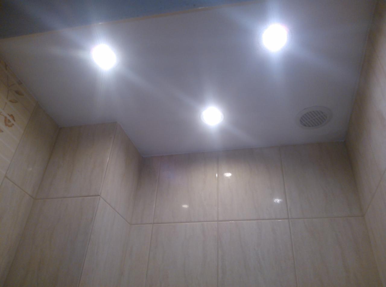 Wykończona łazienka z beżowymi płytkami ściennymi, białym sufitem podwieszanym z trzema punktowymi lampami LED i kratką wentylacyjną.