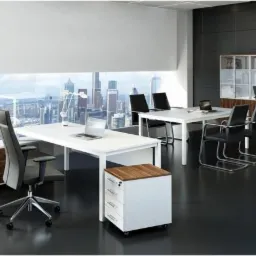 Nowoczesne biuro z białymi biurkami, ergonomicznymi krzesłami, szafkami z drewnianymi akcentami i widokiem na miasto za oknem.